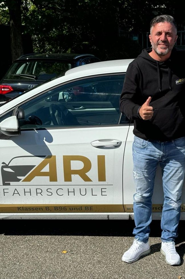 Miftar Rexhepi, Inhaber und Fahrlehrer der Fahrschule ARI, vor einem der Fahrschulwagen.